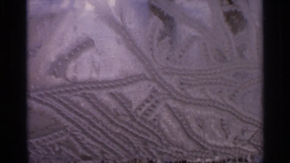 Static 8mm frame from Hamel, Minnesota showing intricate grooves and raised texture on an unidentified carved surface.