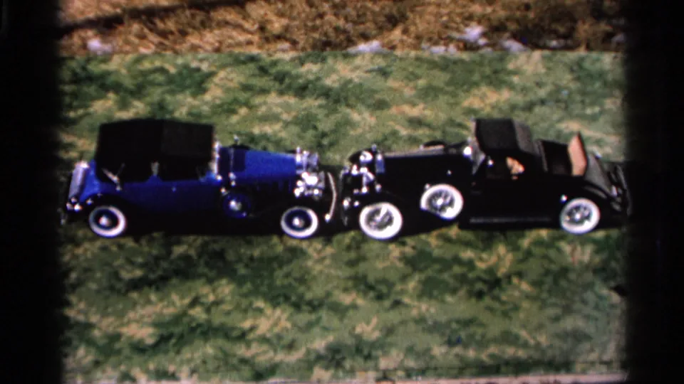 In Hamel, Minnesota per metadata, a blue convertible and black car sit front-to-front on grass with visible contact at their noses.