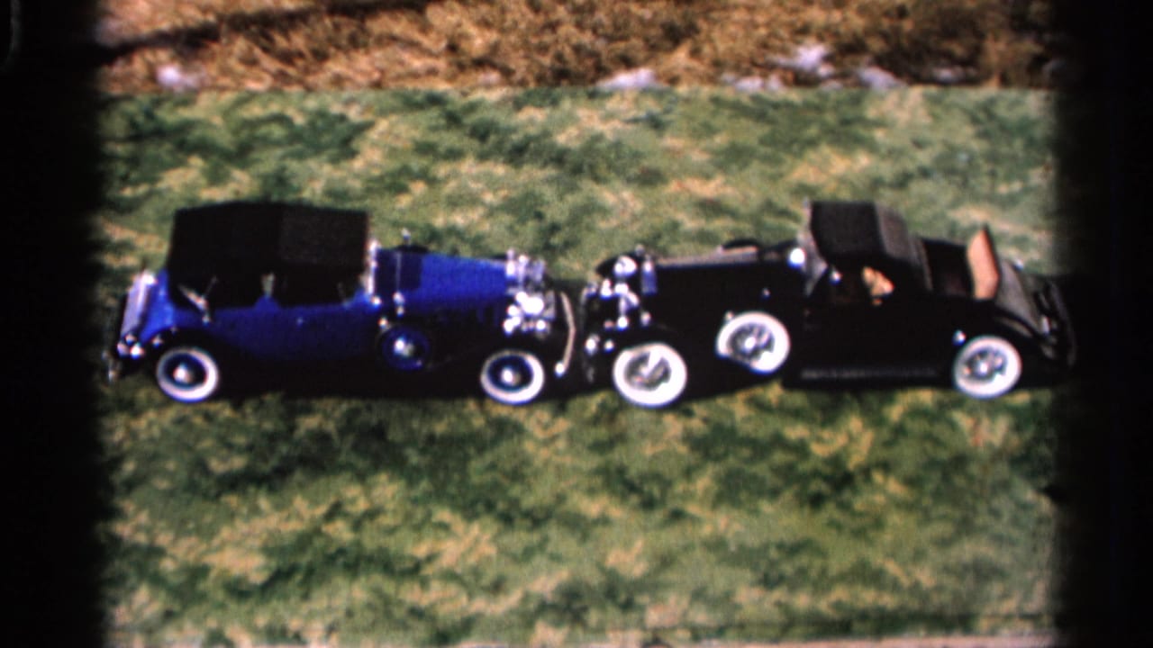 1966 Hamel, Minnesota 8mm frame showing a blue convertible and black roadster parked facing each other on grass.