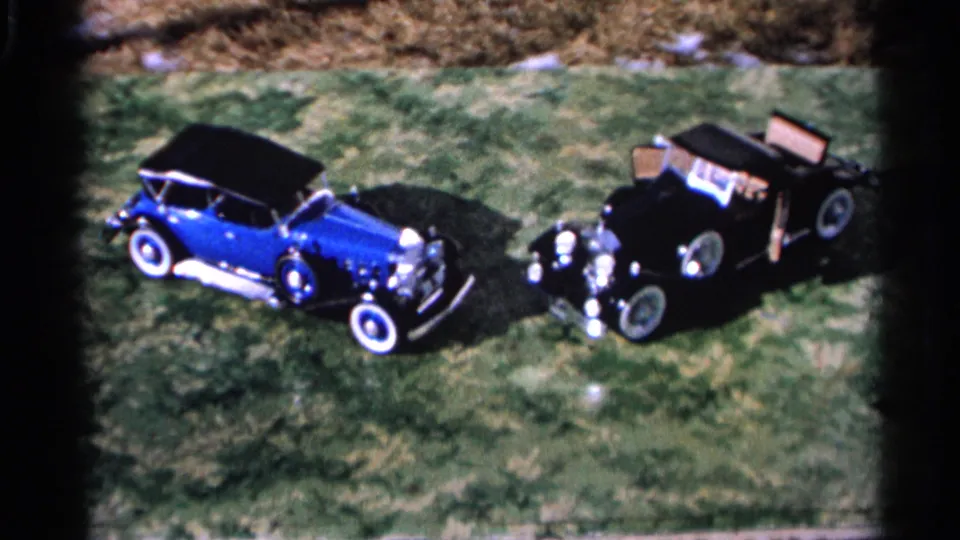 High-angle 8mm frame from Hamel, Minnesota, showing the two parked classic automobiles with soft focus and saturated color.