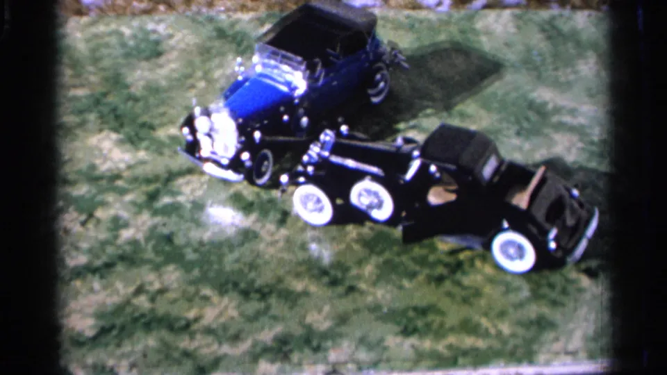 Final 1966 Hamel, Minnesota frame shows the blue and black classic cars from above, with the black car door area visible.