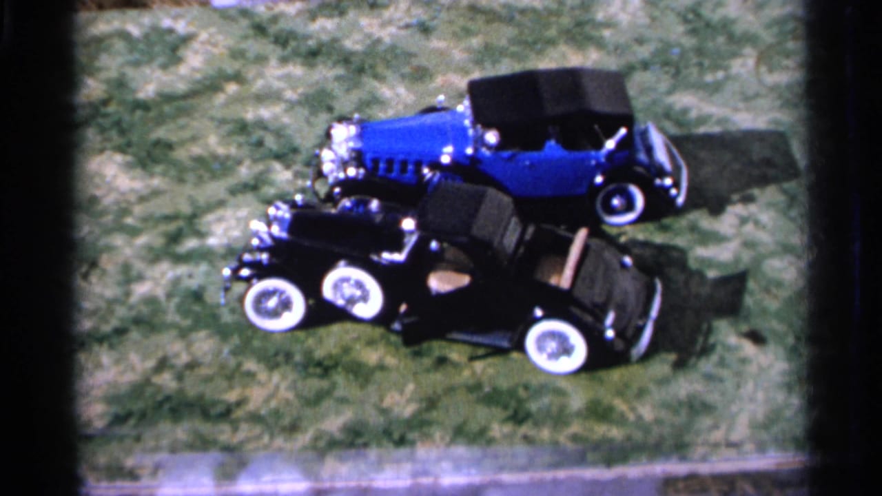 Blue and black toy cars angled on grass with whitewall tires visible.