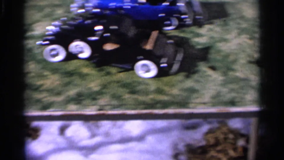 Motion blur trails the two toy cars as they move over the lawn in this 1966 Hamel home-movie frame.