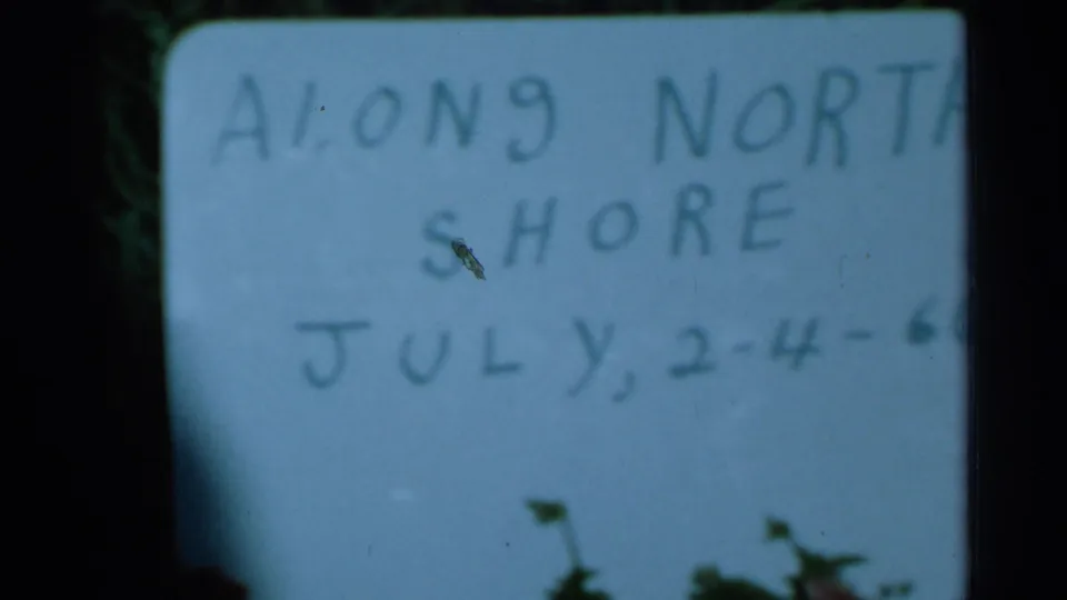 Soft, cropped 8mm frame of the handwritten North Shore title card, with partial July date text visible near the bottom.
