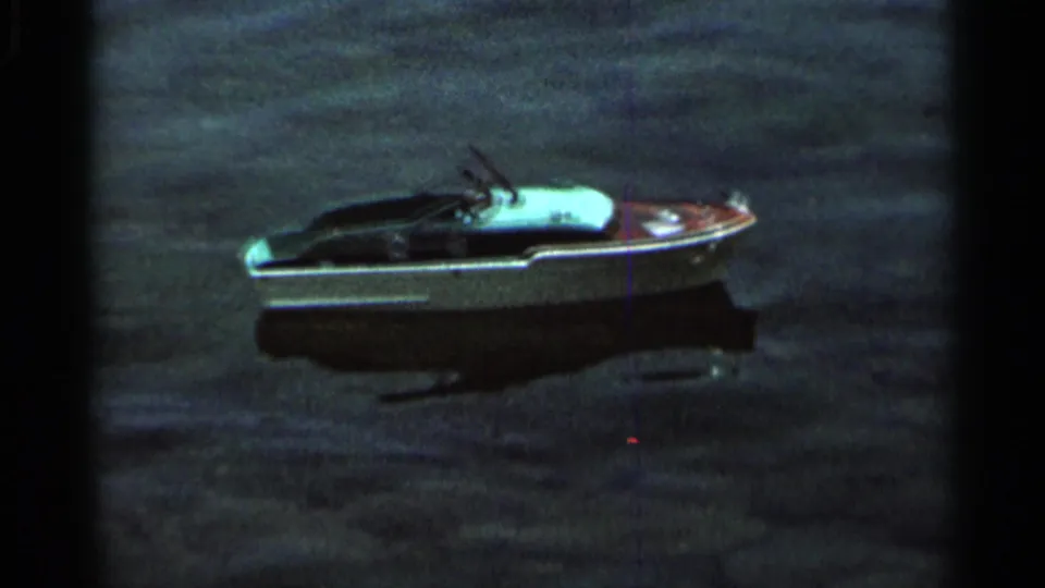 The small toy boat continues across rippled water in the 1966 Hamel, Minnesota home-movie scene, seen in soft 8mm focus.