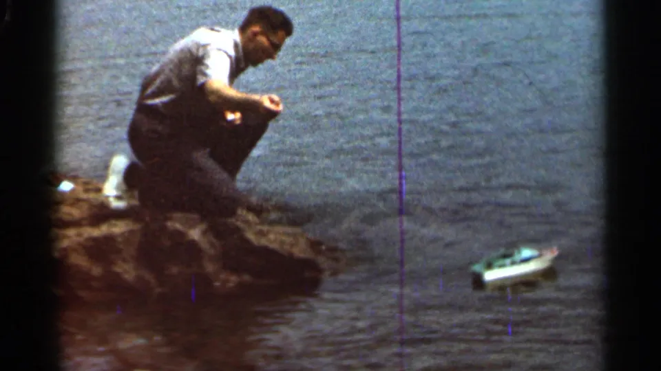 At the end of the 1966 Hamel home-movie clip, the man crouches on the rocks while the miniature boat continues across the lake water.