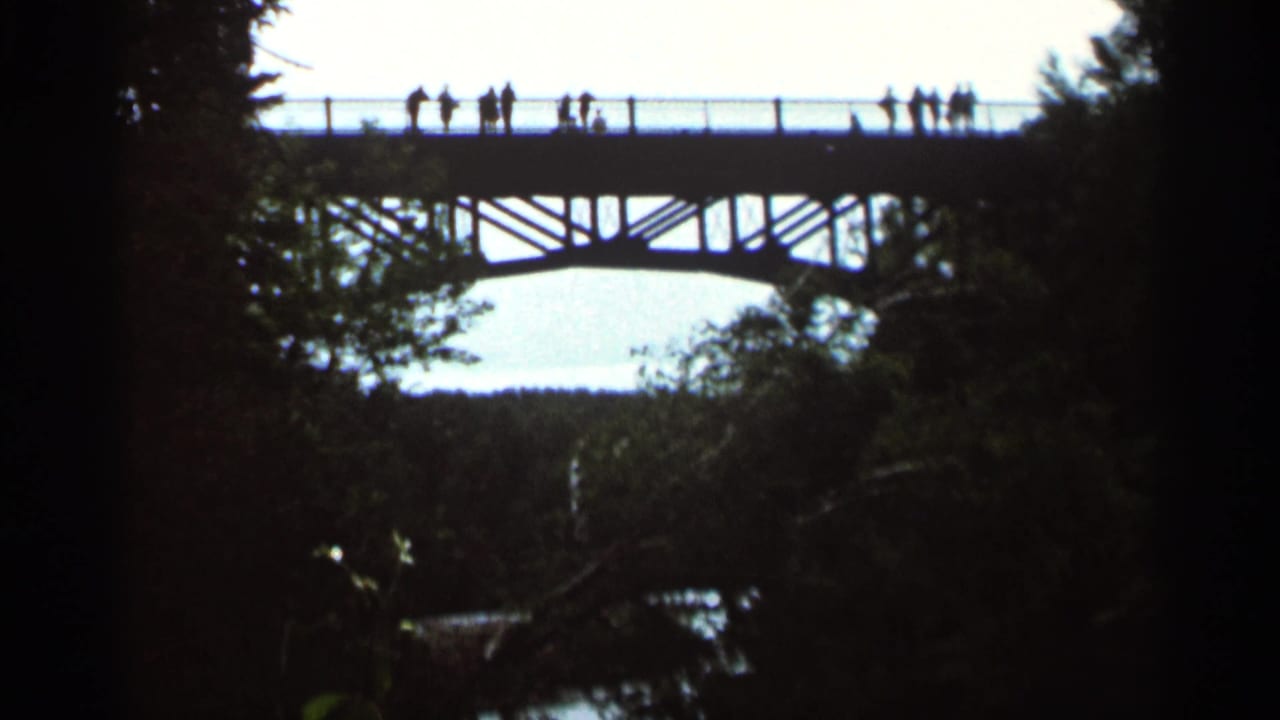 People appear as small silhouettes along the railing of a high bridge.