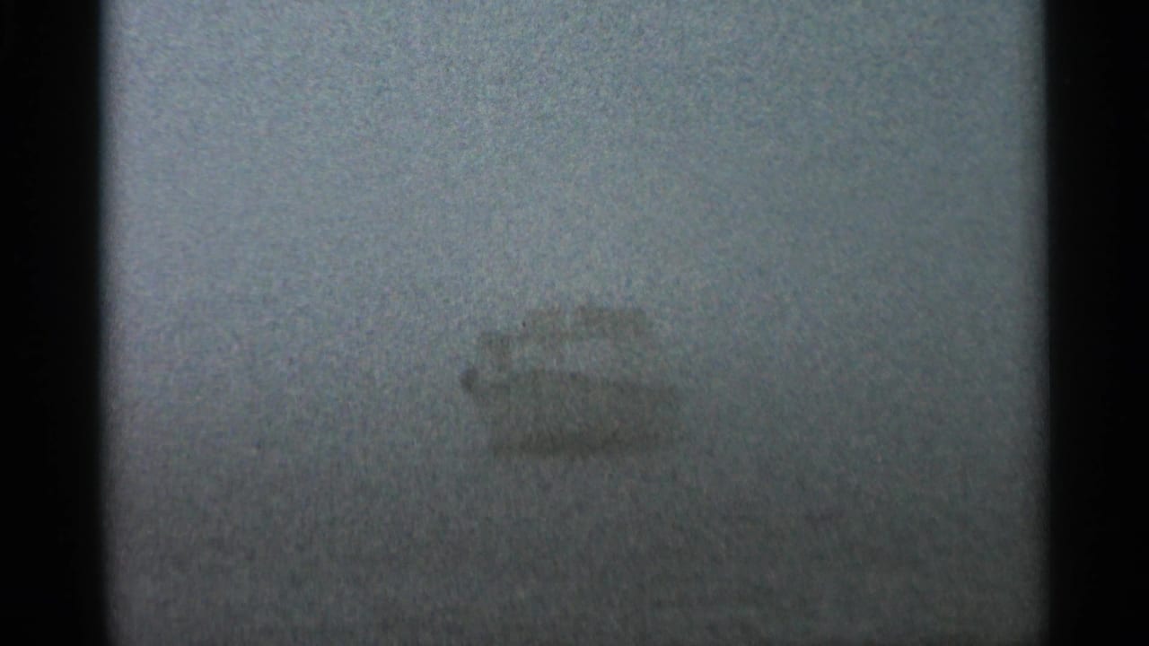 1966 Hamel, Minnesota 8mm frame with a pale boat silhouette partly hidden by dense fog over calm water.