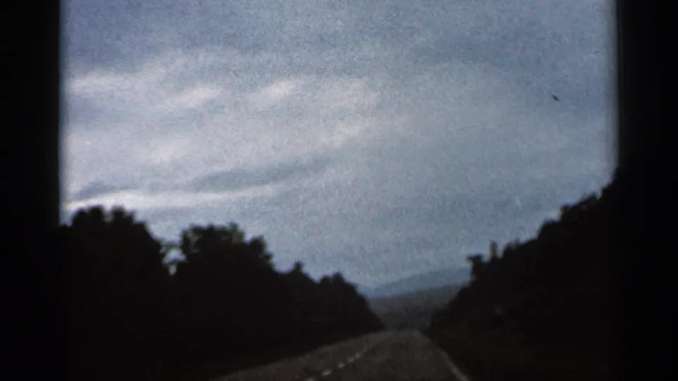 A 1966 Hamel, Minnesota driving view shows an open road framed by trees beneath an overcast sky.