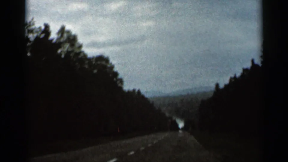 1966 Hamel, Minnesota 8mm still showing a tree-lined rural road and distant light opening ahead.