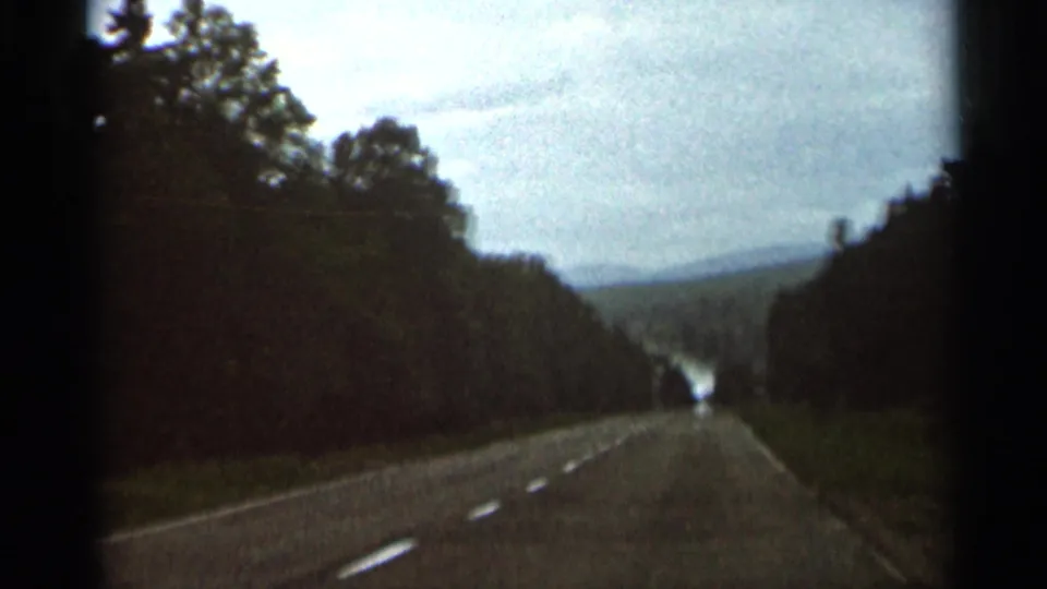 1966 Hamel, Minnesota frame showing a forward-looking car perspective on a rural road bordered by trees.