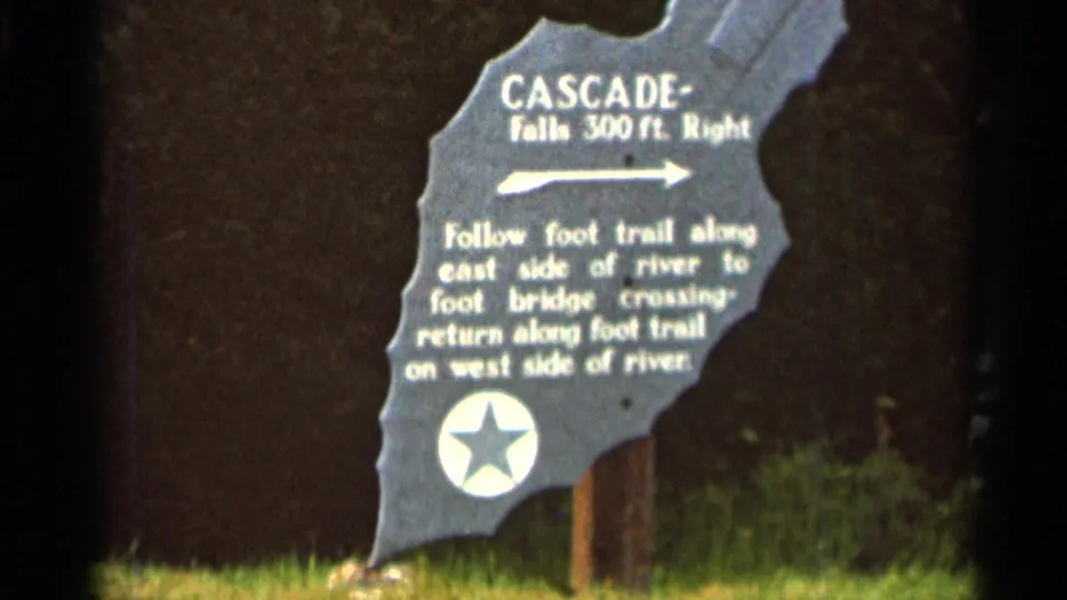1966 8mm frame from Hamel, Minnesota, centered on the Cascade Falls sign and its right-pointing direction arrow.