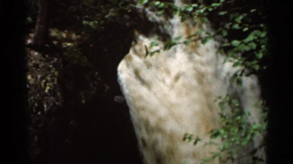 1966 Hamel, Minnesota 8mm frame showing a close waterfall view with green leaves over a bright, textured water surface.
