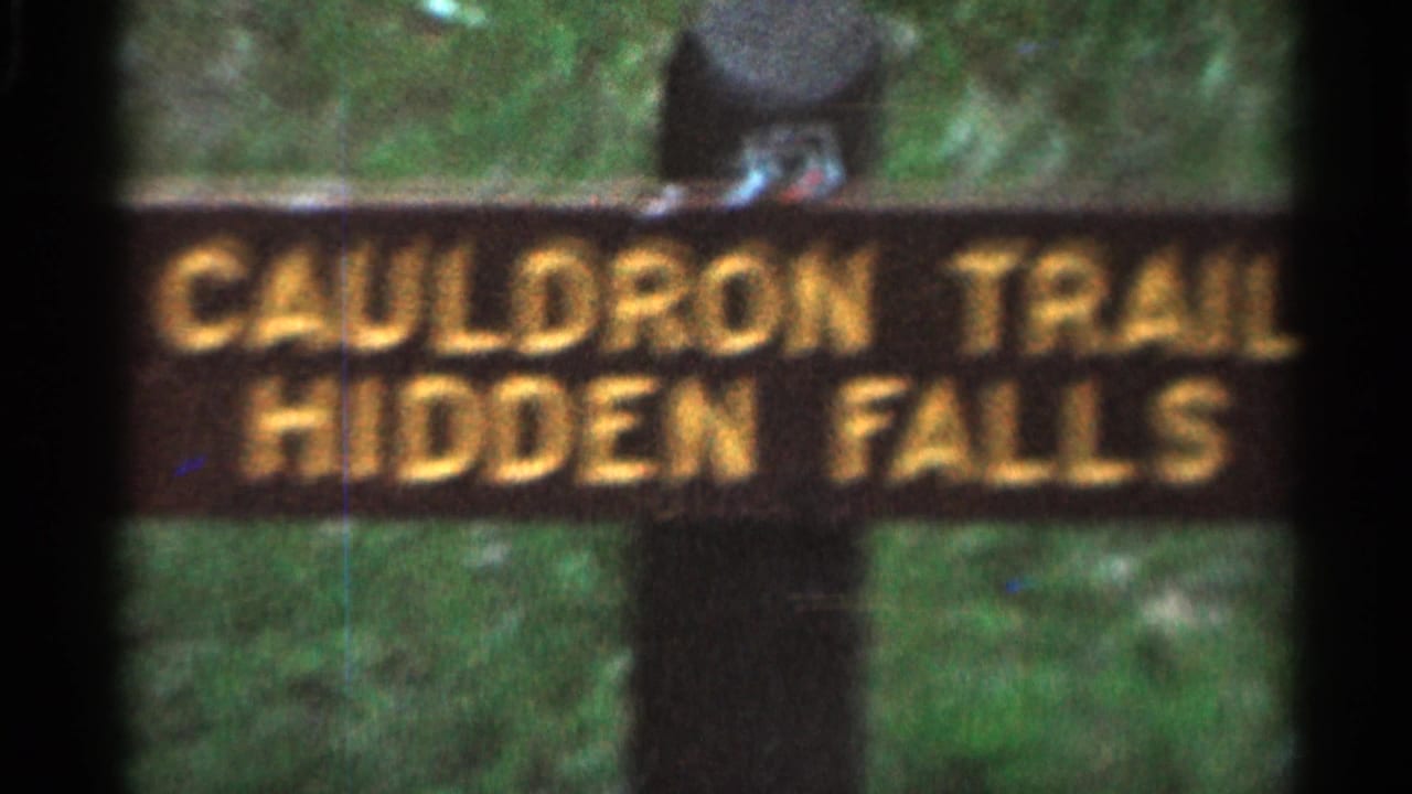 Softer view of the Cauldron Trail Hidden Falls sign beside foliage.