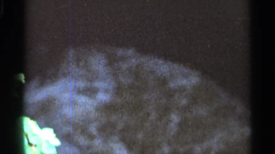 1966 Hamel, Minnesota 8mm frame showing blurred stream water and foam over rocks with prominent film grain and scratches.