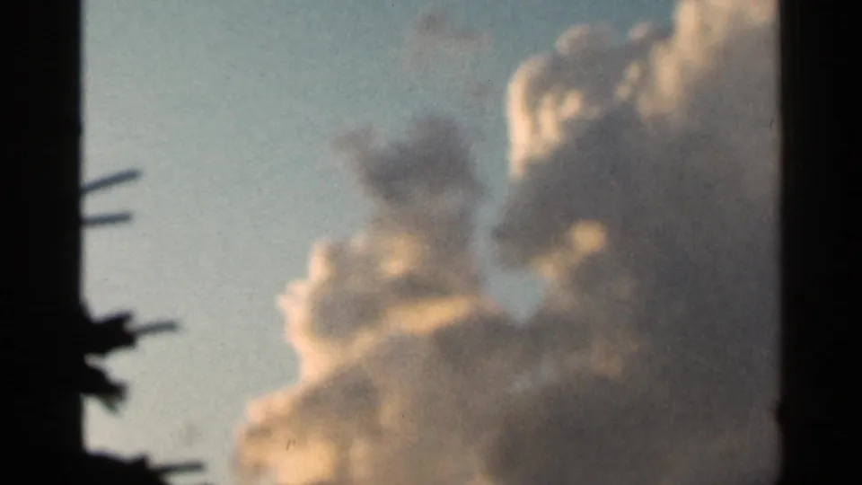 Soft, sunlit clouds are framed by dark 8mm gate edges in the final 1966 Hamel, Minnesota home-movie frame.