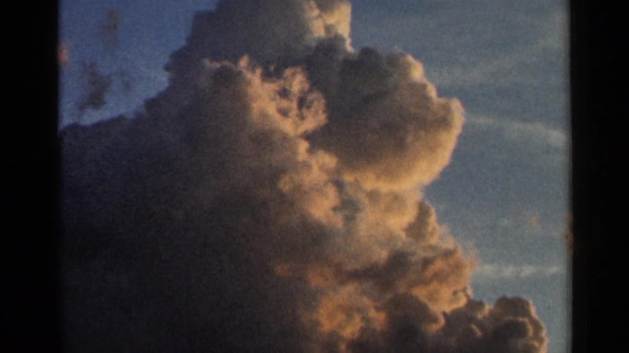 Large cumulus cloud glowing gold and orange against a deep blue sky.