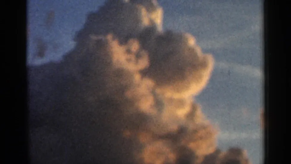 1966 Hamel, Minnesota 8mm frame showing a soft, warm-toned cumulus cloud dominating the sunset sky.