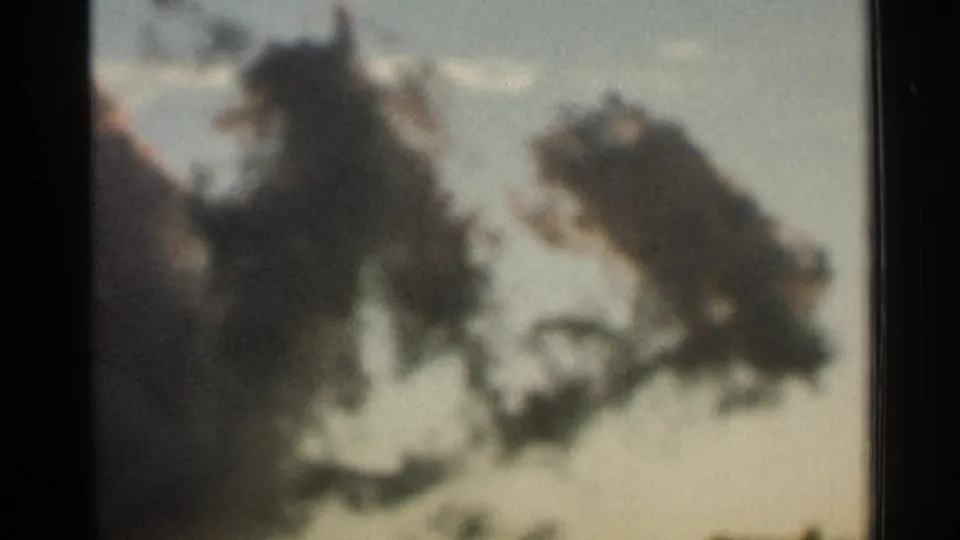 1966 Hamel, Minnesota home-movie still showing low, diffuse cloud shapes with soft grain and muted color.