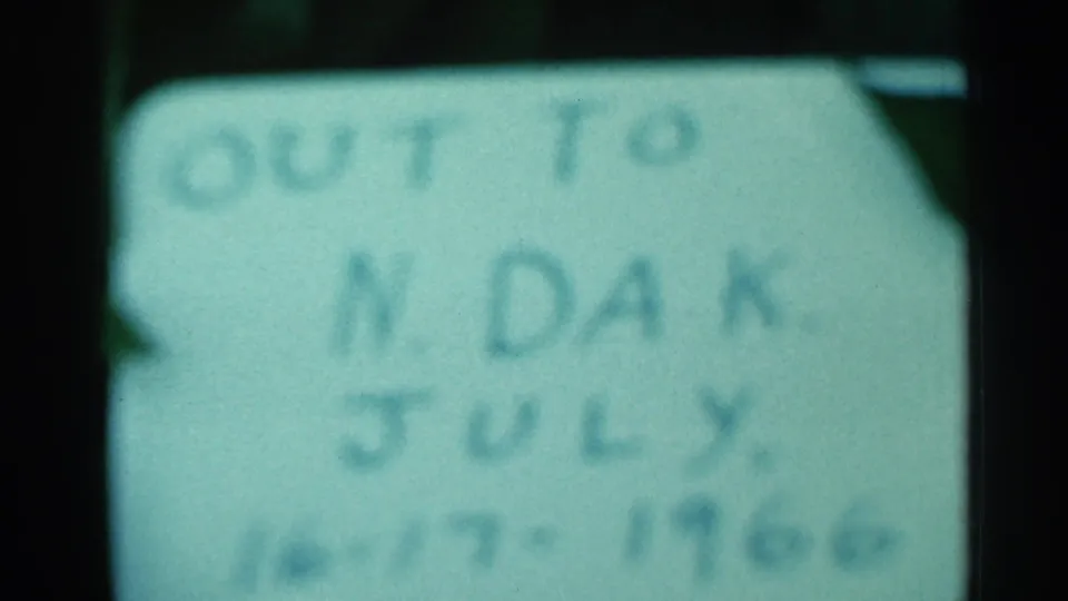 Blurred 1966 8mm view of the handwritten North Dakota July travel note, with dark frame borders and greenish cast.