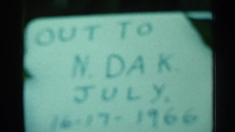 Soft 8mm frame showing the handwritten North Dakota July 1966 note, heavily blurred but still partly legible.