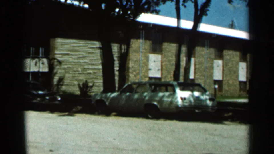 1966 Hamel, Minnesota frame with a light station wagon in the foreground and a stone-faced building behind it.