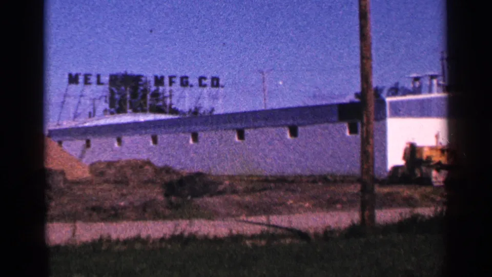 1966 Hamel, Minnesota frame showing the long warehouse side, MELROSE MFG. CO. lettering, a dirt mound, and equipment in the yard.
