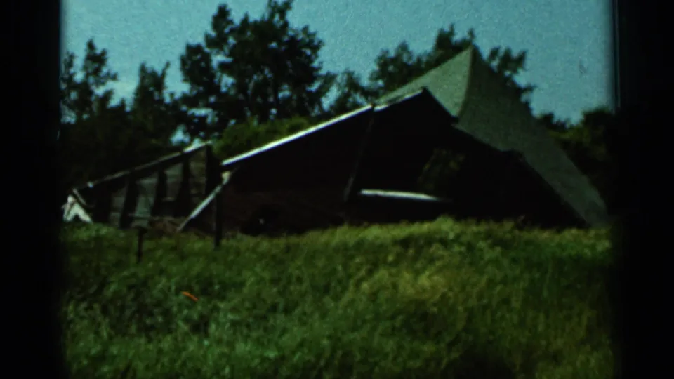 1966 Hamel, Minnesota 8mm frame showing a farm windmill above trees and tall green grass.