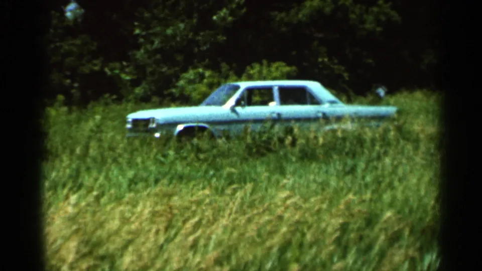 A turquoise classic sedan sits in tall grass in Hamel, Minnesota, 1966, seen in soft 8mm color home-movie footage.