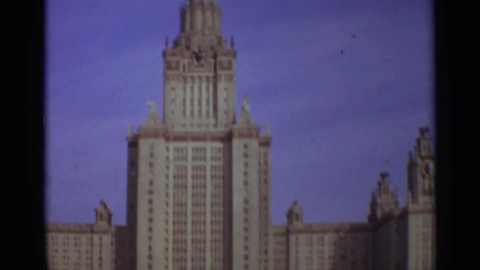 1966 Moscow home-movie frame showing the central tower of Moscow State University under a bright blue sky.