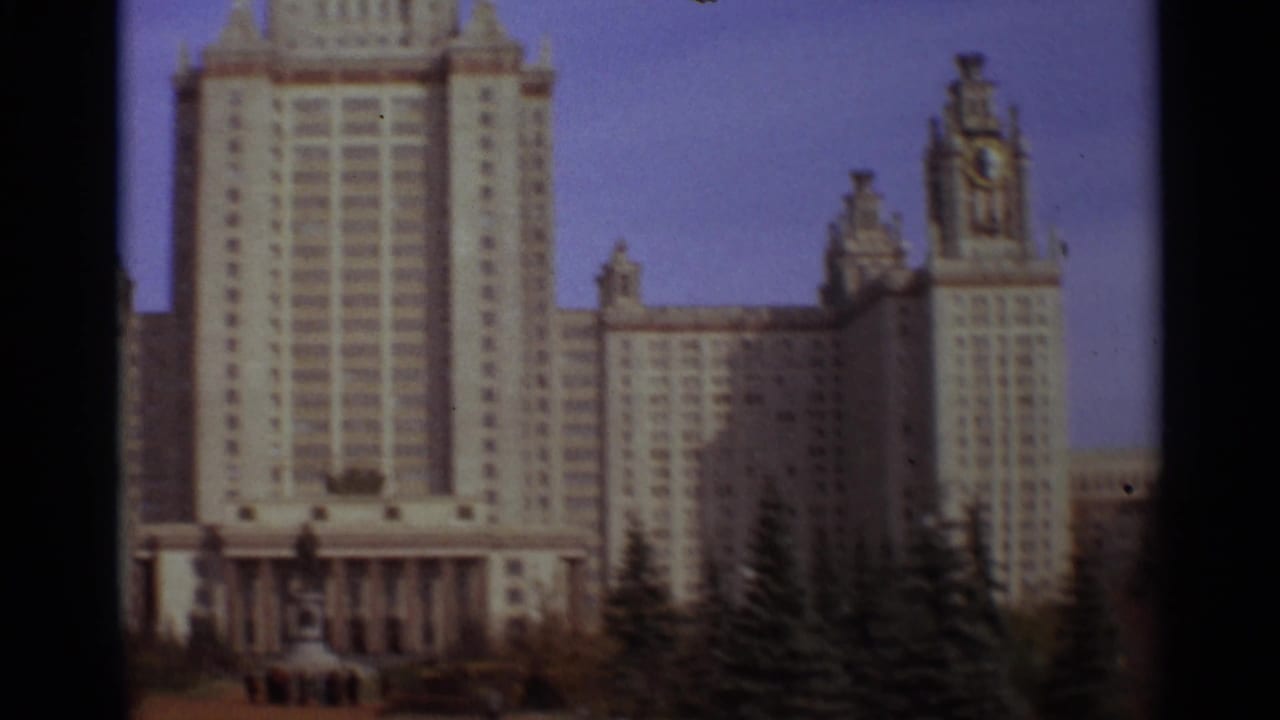 Wide view of the Moscow State University facade with trees and open grounds below.