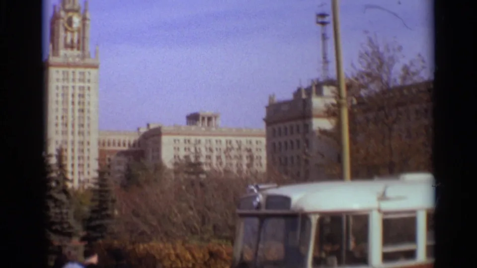1966 Moscow frame showing a light blue bus in the foreground with Moscow State University and campus trees behind it.