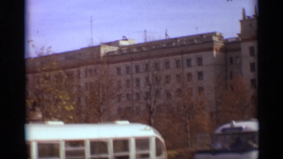 1966 Moscow street scene with autumn trees, a large Soviet-era facade, and bus roofs at the lower edge.