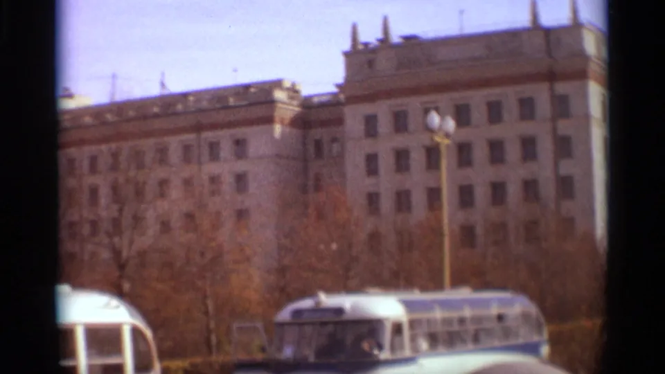 1966 Moscow view with a bus at lower right, lampposts, autumn trees, and a large Soviet-era building behind.