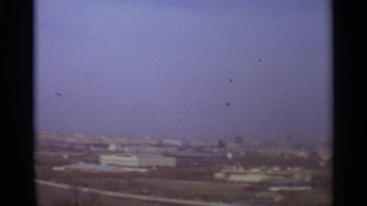 Distant city view across open riverfront or embankment land.