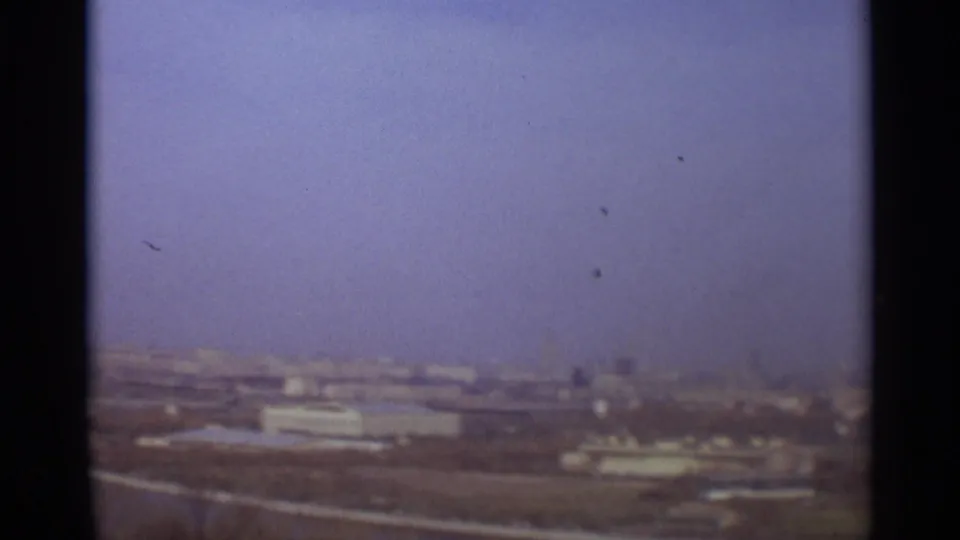 Hazy 1966 Moscow panorama with low buildings, open ground, riverbank lines, and a pale blue-violet sky.