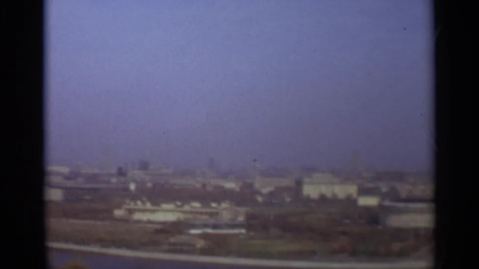 Distant Moscow cityscape from 1966 showing low structures, open riverfront land, and a soft blue-violet sky.