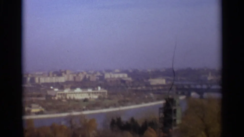 1966 Moscow frame showing river water, a bridge or embankment, distant buildings, and foreground trees.