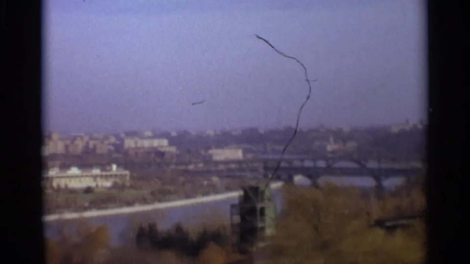 1966 Moscow home-movie frame showing a hazy river panorama with arched bridges, autumn trees, and distant buildings.