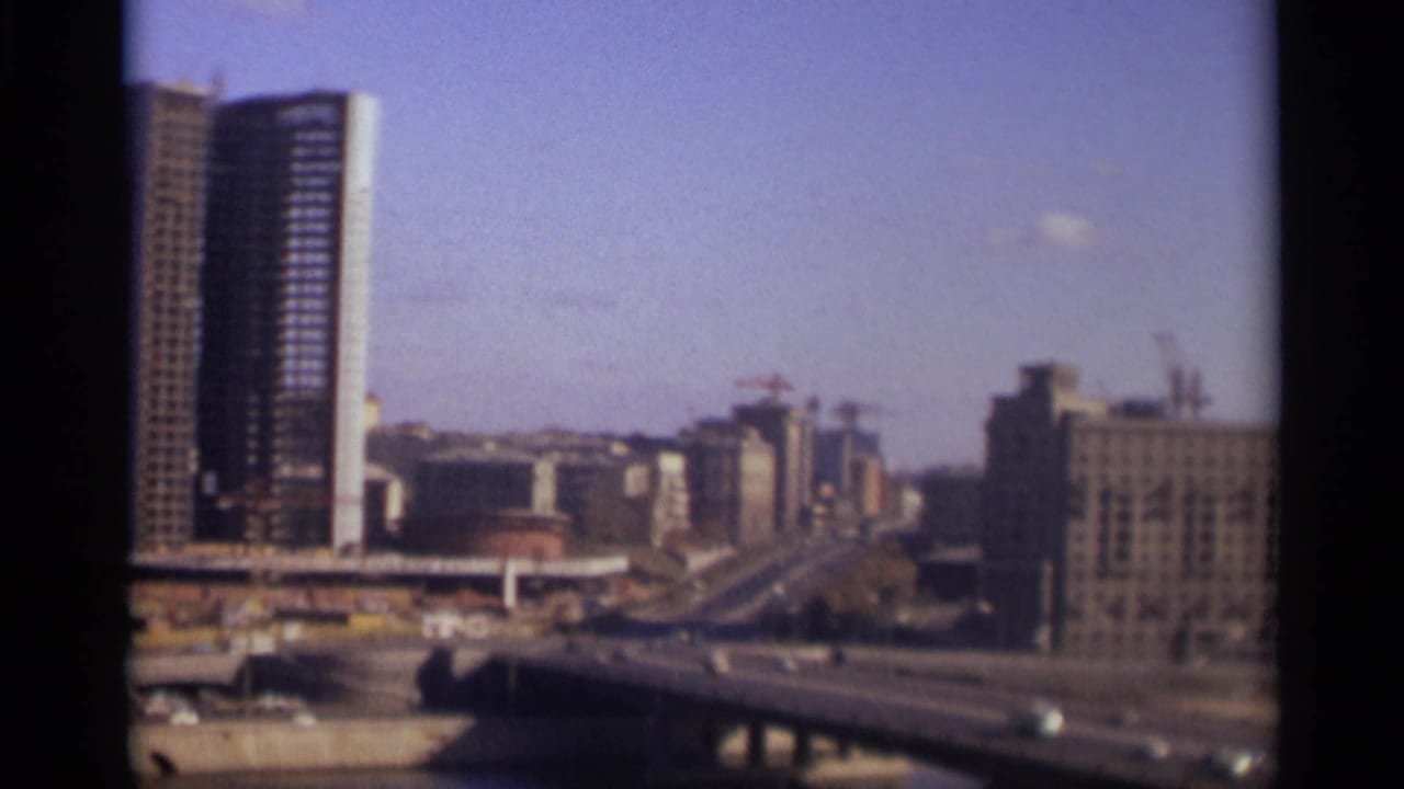 A multi-lane bridge carries cars past a tall tower and distant buildings.