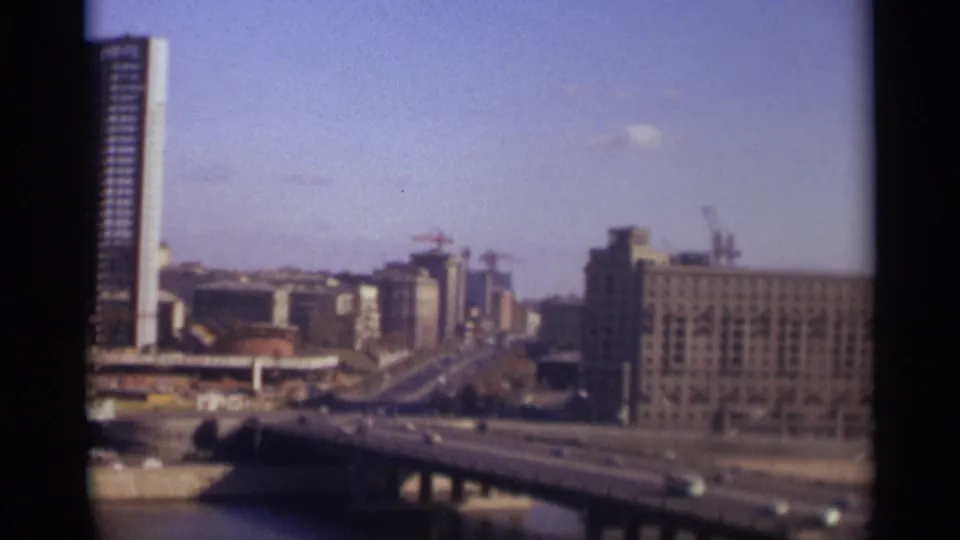 1966 Moscow home-movie view of bridge traffic, water, cranes, and large rectangular buildings under a clear sky.