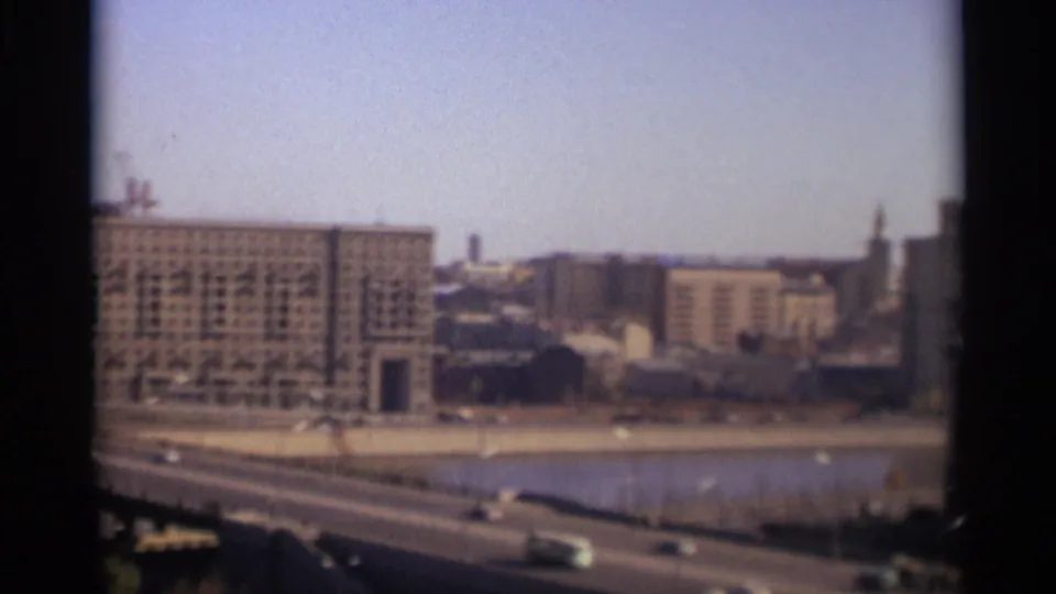 1966 Moscow frame near the end of the pan, showing bridge traffic, river water, a large building, city blocks, and a distant vertical tower.