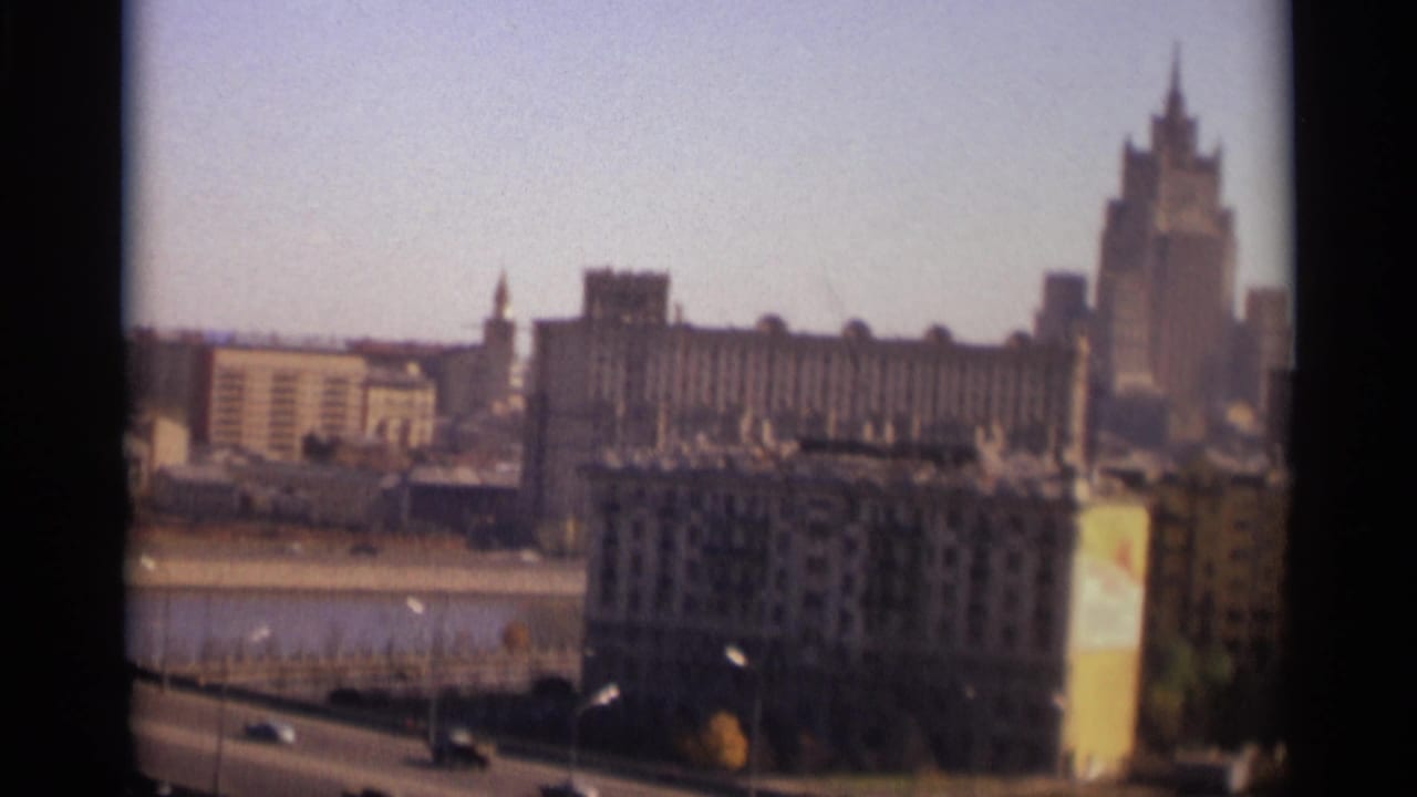 Soft 8mm view of Moscow skyline beyond a river and roadway with cars.