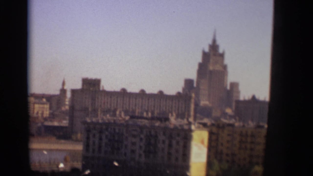 Hazy Moscow skyline with a spired monumental skyscraper above foreground buildings.