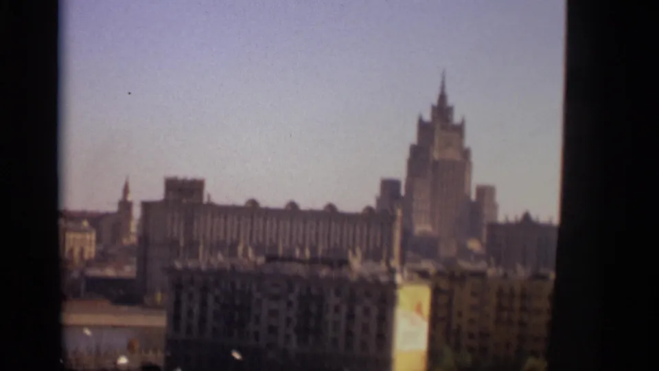 Moscow skyline in 1966 with a prominent spired tower, long facade, and foreground urban blocks on 8mm film.