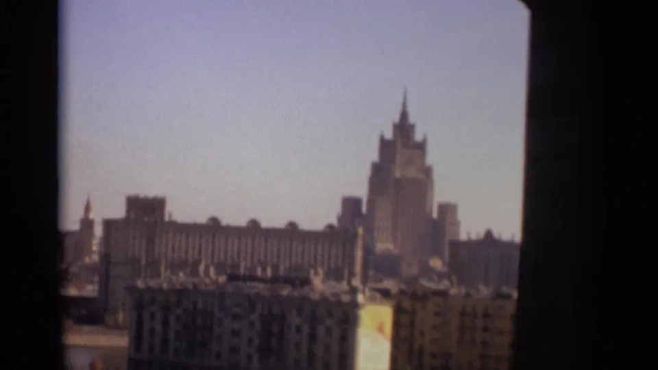 1966 Moscow cityscape frame with a spired monumental high-rise seen beyond lower residential or office blocks.