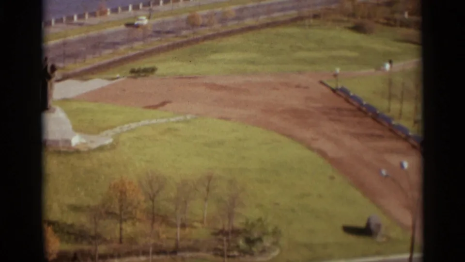 1966 Moscow park view from above, with a monument partly at left, open lawns, a curving path, roadside, and tiny pedestrians.