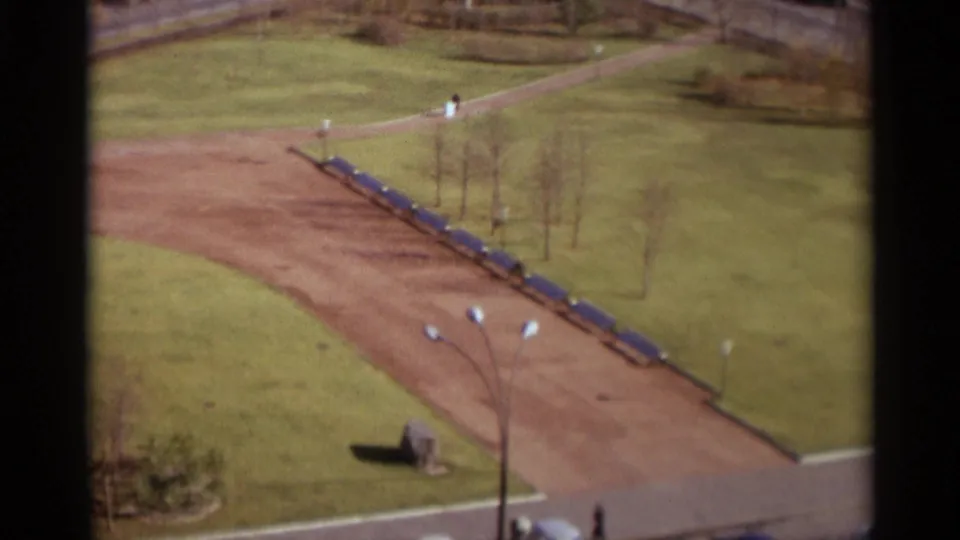 Elevated 1966 Moscow park view with a curving dirt walkway, blue bench row, lawns, and small distant figures.