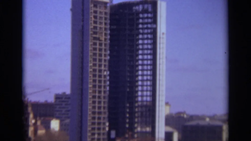 1966 Moscow 8mm frame showing a partially completed tower with gridded facade, nearby crane, and low urban buildings below.