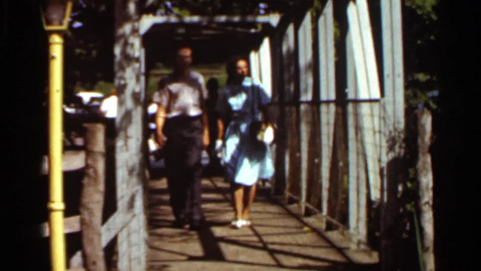 Near the end of the 1966 Saint Louis clip, the adults are close to camera on the walkway, with the white metal side structure and yellow post prominent.